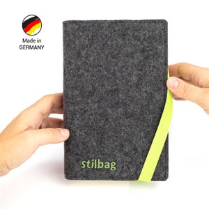 May include: A gray felt case with a lime green zipper pull. The case has the text "stillbag" embroidered on the front. Made in Germany.