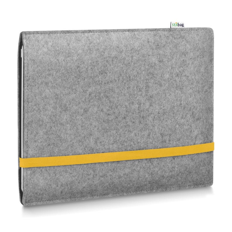 May include: A rectangular light gray felt laptop sleeve featuring a horizontal bright yellow elastic band across the front. A small white fabric tag with the text stilbag is attached to the top edge of the sleeve, which holds a thin electronic device.