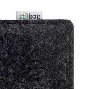 May include: A close-up of a black felt fabric planter with a white label that says "stilbag" in green letters.