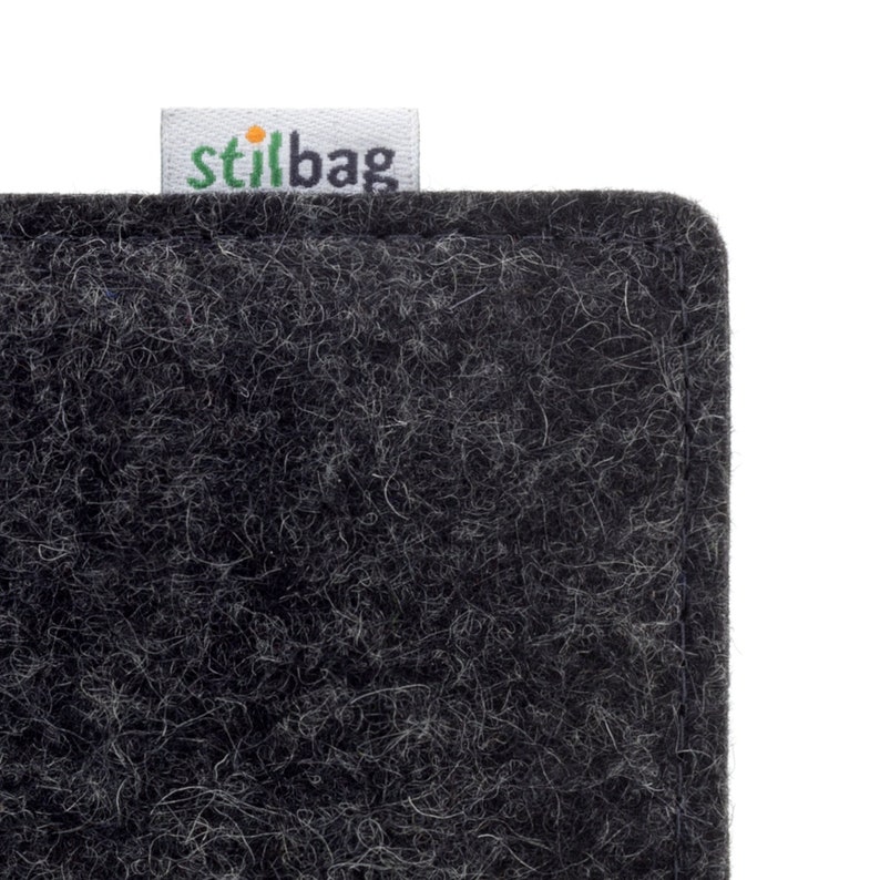 May include: A close-up of a black felt fabric planter with a white label that says "stilbag" in green letters.
