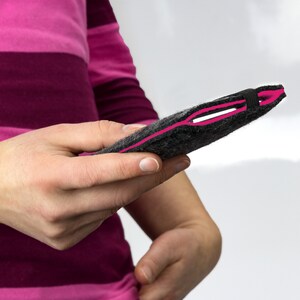 May include: A gray felt phone case with a pink seam and a black elastic band.