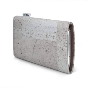 Puede incluir: Una cartera de corcho gris claro con la palabra "stilbag" impresa en la parte delantera.