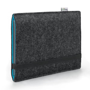 Può includere: Una custodia per laptop in feltro grigio con una fascia elastica nera e un bordo blu. La custodia ha la scritta "stilbag" stampata nell'angolo in alto a destra.