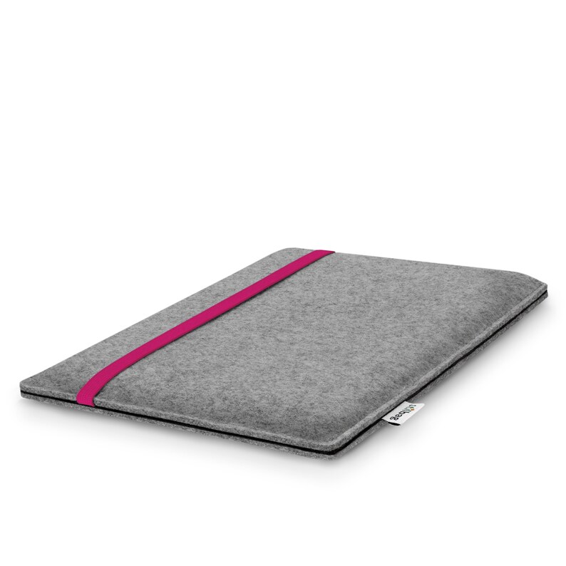 May include: A rectangular gray felt laptop sleeve featuring a vibrant magenta elastic band stretched across the front cover. The sleeve has a slim profile with black edge detailing and a small white fabric tag with black text on the side.