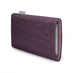 May include: A purple cork phone case with a soft, rounded design. The case has a textured surface and a small "stilbag" label. A silver smartphone is partially visible inside the case.