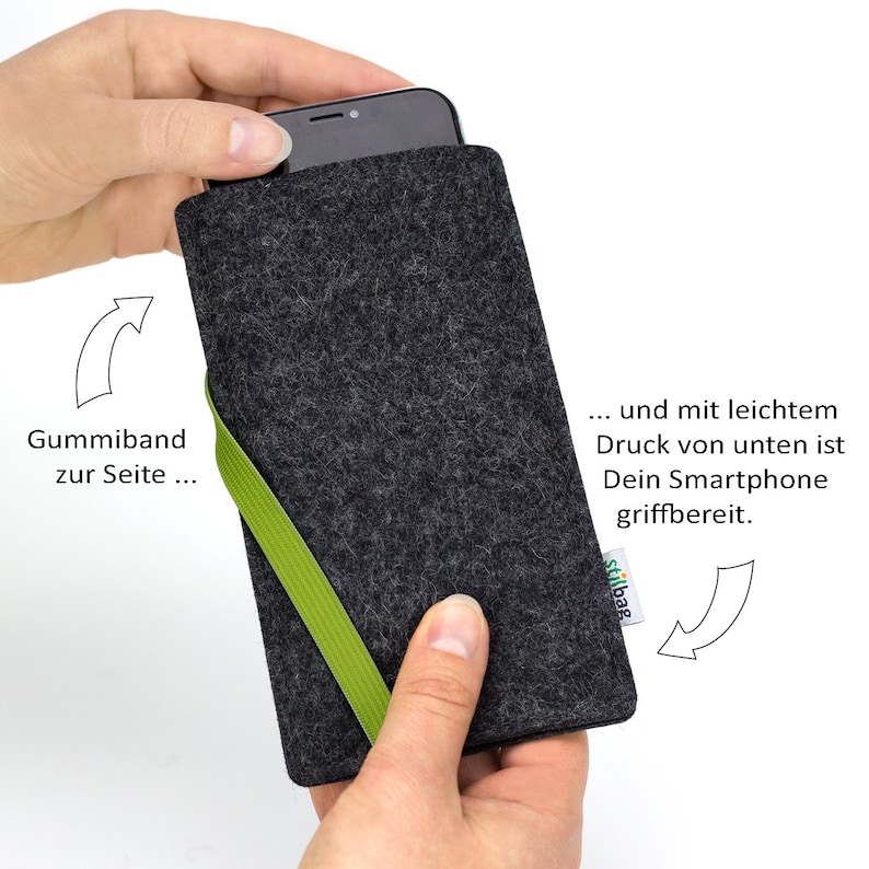 May include: A gray felt phone case with a green elastic band. The text "stilbag" is printed on the case. The case is designed to hold a smartphone securely.