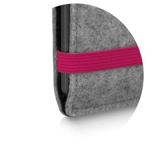 May include: A grey felt sleeve case featuring a dark grey interior edge and a bright pink elastic band wrapped horizontally around the exterior. The sleeve has a textured, fibrous surface and rounded corners, designed to hold a thin electronic device.
