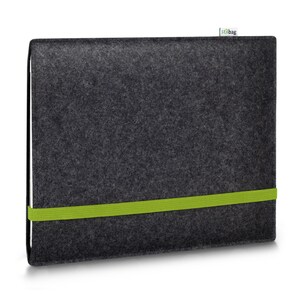 May include: A dark charcoal gray felt laptop sleeve featuring a vibrant lime green elastic band wrapped horizontally around the center to secure the closure. A small white fabric tag with the text stilbag is attached to the top edge.