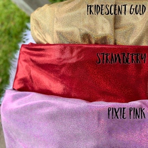 Puede incluir: Tres muestras de tela iridiscente en tonos dorados, rojos y rosados. La tela est&aacute; etiquetada como "Iridescent Gold", "Strawberry" y "Pixie Pink".