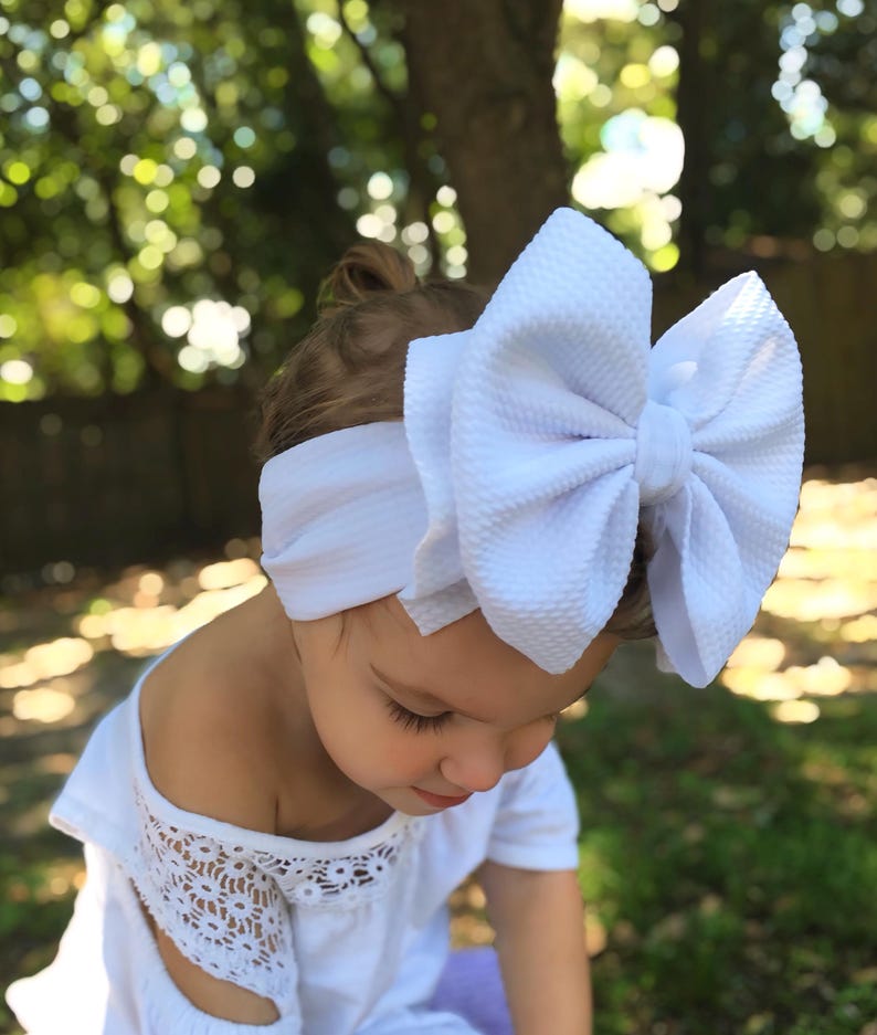 May include: A white ceramic mug with a black handle and the text "But First, Coffee" in a bold, black font. The mug is set against a blurred background, suggesting a cozy setting.