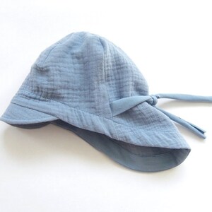 May include: A light blue sun hat with a wide brim and a tie at the back.