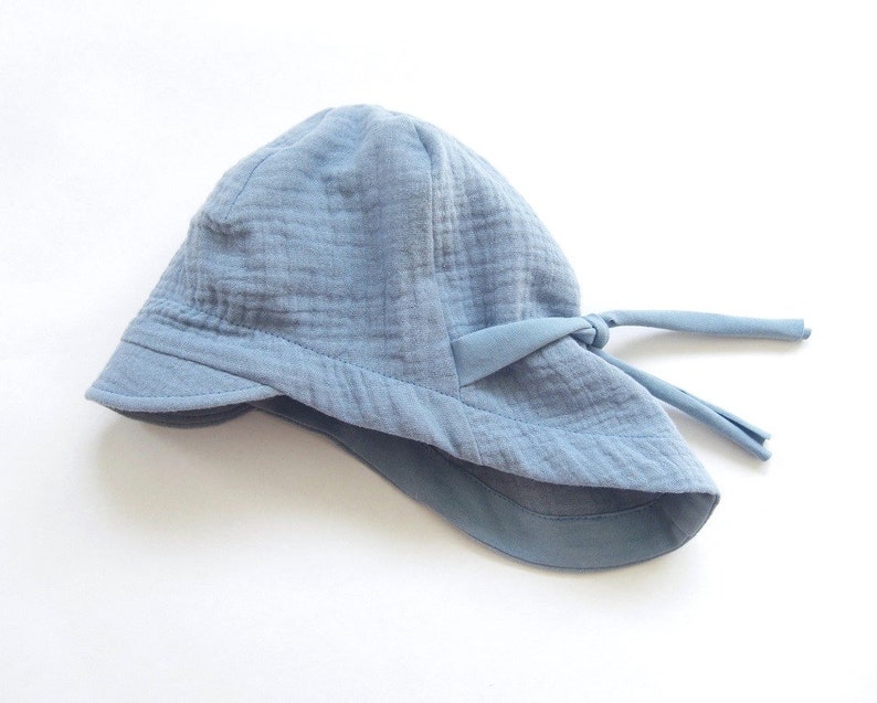 May include: A light blue sun hat with a wide brim and a tie at the back.