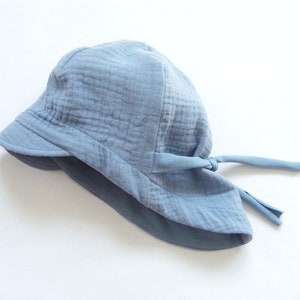 May include: A light blue sun hat with a wide brim and a tie at the back.
