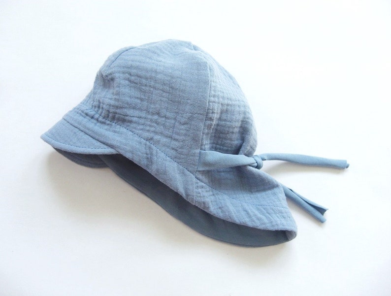 May include: A light blue sun hat with a wide brim and a tie at the back.