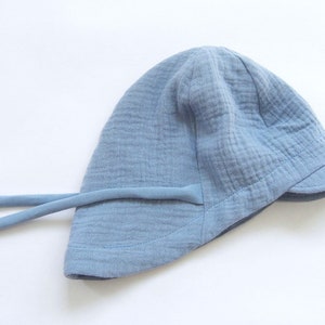 May include: A light blue sun hat with a wide brim and a tie string. The hat is made of a soft, textured fabric.