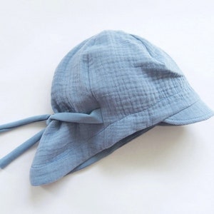 May include: A light blue cotton sun hat with a wide brim and a tie at the back.