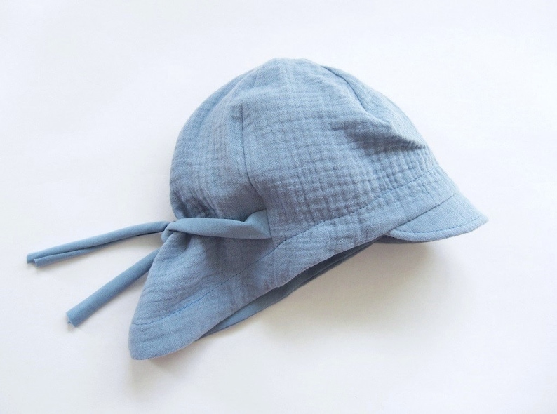 May include: A light blue cotton sun hat with a wide brim and a tie at the back.