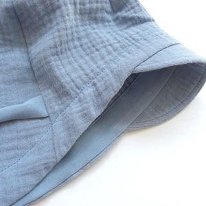 May include: A light blue cotton bucket hat with a wide brim and a sewn-in band around the crown.