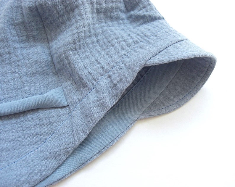 May include: A light blue cotton bucket hat with a wide brim and a sewn-in band around the crown.