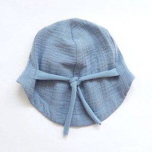 May include: A light blue cotton sun hat with a tie at the top.
