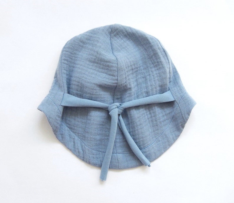 May include: A light blue cotton sun hat with a tie at the top.