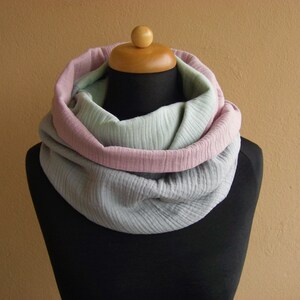May include: A soft, cozy infinity scarf in shades of gray, pink, and green. The scarf is made of a lightweight fabric and is perfect for layering in the cooler months.