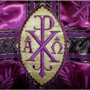 May include: Close-up of a purple and gold religious garment. The design features a central embroidered emblem with the Chi Rho symbol, along with the Greek letters Alpha and Omega. The background is a rich, textured purple fabric with decorative trim.