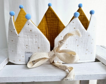 Op de afbeelding: Een witte kroon met gouden glitter en blauwe pompoenen. De kroon is gemaakt van zachte stof en heeft een strik sluiting.