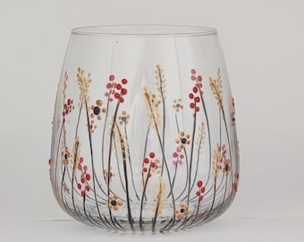 May include: A clear glass wine glass with a hand-painted design of red and yellow flowers on the side.