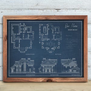 May include: Framed blueprint of a house, featuring floor plans and elevations. The blueprint is on a blue background with white lines, showing the basement and first floor plans, and south, east, and west elevations. The text "Our Home" and address are visible.