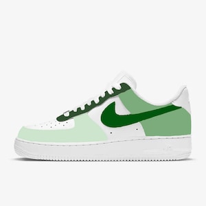 May include: White low-top sneakers with a green and light green color block design. The Nike swoosh is green.