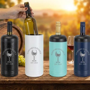 May include: Four wine bottle chillers in black, white, teal, and navy blue, each with a black top. The text "VINEYARD ELEGANCE" and "EST. 2024" are printed on the front. A hand is inserting a wine bottle into the white chiller.