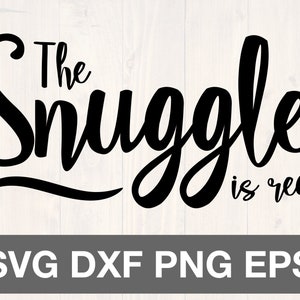 Op de afbeelding: Zwarte tekst op een lichte houtnerf achtergrond leest "The Snuggle is real." Daaronder een grijze rechthoek met de witte woorden "SVG DXF PNG EPS". Geschikt voor digitale knutselprojecten.