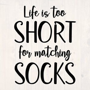 以下が含まれることがあります： 白い木製の背景に黒いテキストのデザインで「Life is too SHORT for matching SOCKS」と書かれています。画像には、「SVG」、「EPS」、「DXF」、「PNG」というテキストが入った青い円も含まれています。