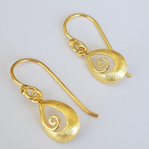 Puede incluir: Un par de pendientes de oro con forma de lágrima texturizada y un delicado diseño de espiral.