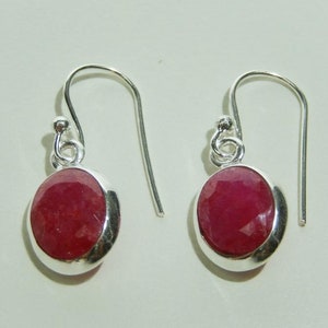 May include: A pair of silver dangle earrings with red gemstone drops. The earrings have a simple design and are perfect for everyday wear.