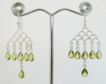 May include: Silver dangle earrings with a chandelier design featuring multiple pear-shaped green gemstones.
