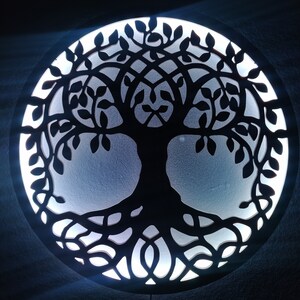 May include: A black wooden wall decor featuring a tree of life design with intricate branches and roots. The tree is illuminated from behind with a white light, creating a glowing effect.