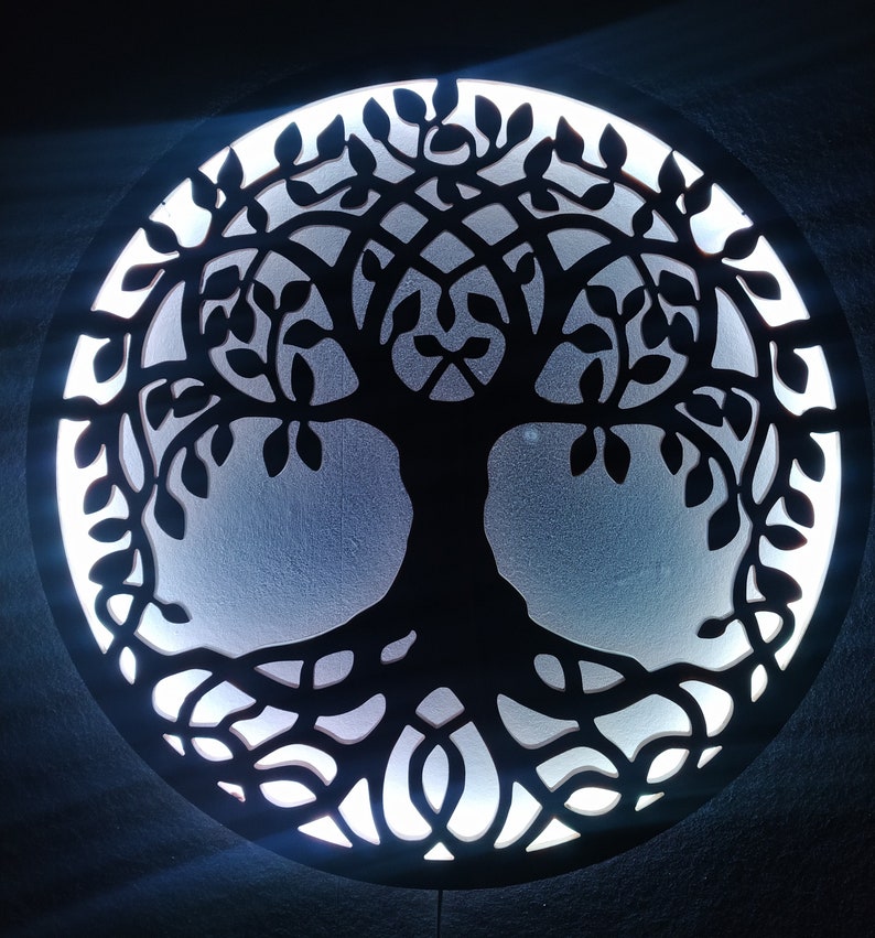 May include: A black wooden wall decor featuring a tree of life design with intricate branches and roots. The tree is illuminated from behind with a white light, creating a glowing effect.