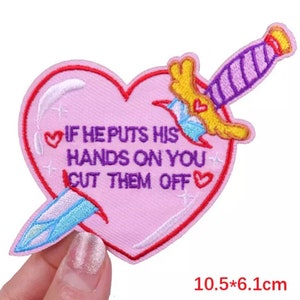 May include: Pink heart-shaped embroidered patch with a dagger piercing through it. The patch has the text "If he puts his hands on you cut them off" with a small heart symbol before and after the text.
