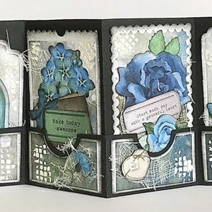 May include: A black card with four panels, each decorated with a different design. The first panel features a blue door with the word "DREAM" above it. The second panel has a bouquet of blue flowers in a brown pot with the text "Make today awesome". The third panel has a blue rose with the text "Start each day with a grateful heart". The fourth panel has a butterfly with the text "Good things take time".