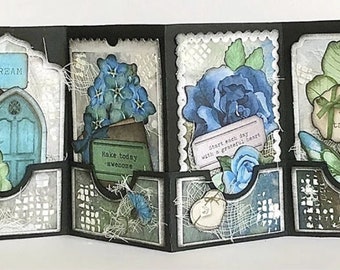 Pode incluir: Um cartão preto com quatro painéis, cada um decorado com um design diferente. O primeiro painel apresenta uma porta azul com a palavra "DREAM" acima. O segundo painel tem um buquê de flores azuis em um vaso marrom com o texto "Make today awesome". O terceiro painel tem uma rosa azul com o texto "Start each day with a grateful heart". O quarto painel tem uma borboleta com o texto "Good things take time".