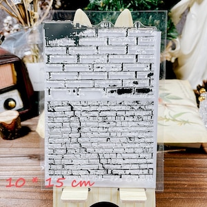 以下が含まれることがあります： レンガの壁のデザインのクリアスタンプ。スタンプのサイズは10cm x 15cmです。黒いレンガのパターンは、使い古された、古くなった外観をしています。スクラップブッキングやクラフトプロジェクトに最適です。