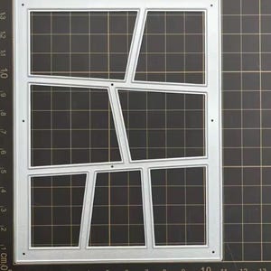 May include: A silver metal die cut in a rectangular shape with six irregular rectangular openings. The die cut has small holes in each corner. The background is a black grid.