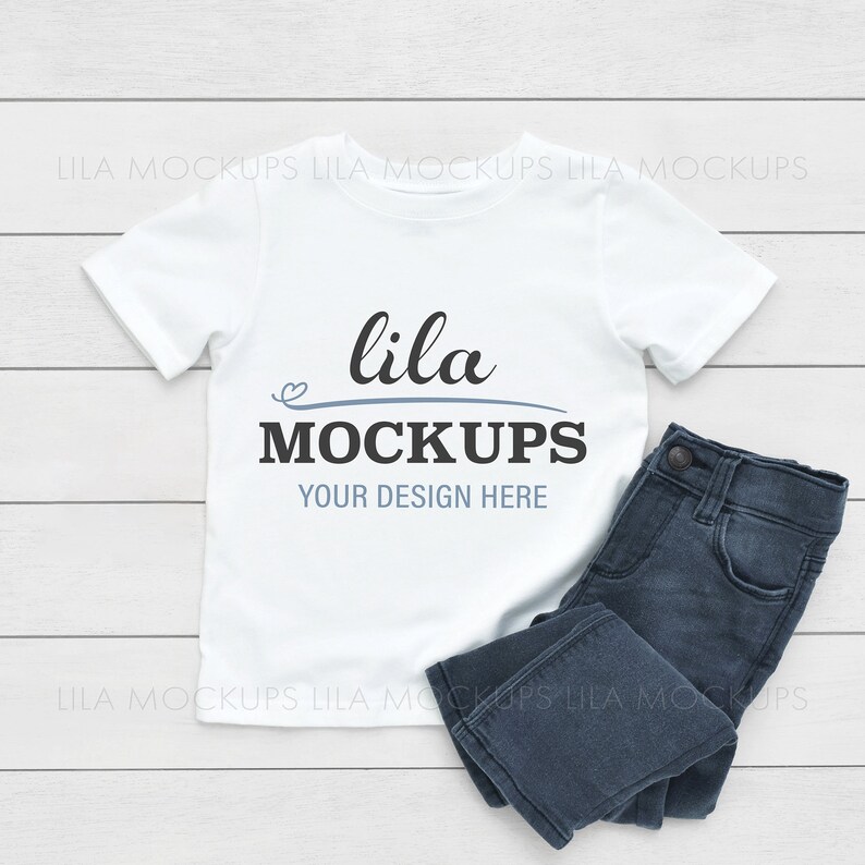 Puede incluir: Camiseta blanca con un dise&ntilde;o azul y negro que dice "lila MOCKUPS YOUR DESIGN HERE" sobre un fondo de madera blanca con pantalones vaqueros azules.