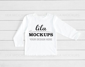 Puede incluir: Maqueta de camiseta blanca de manga larga con el texto "lila MOCKUPS YOUR DESIGN HERE" sobre un fondo de madera blanca.