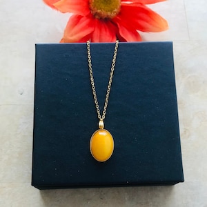 May include: A gold chain necklace with a yellow oval pendant. The pendant is set in a gold bezel.