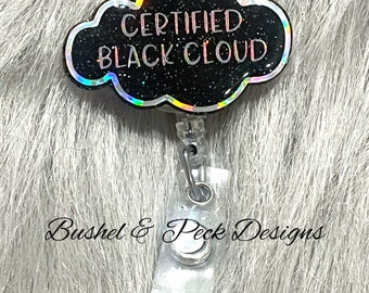 以下が含まれることがあります： 銀色のクリップと「CERTIFIED BLACK CLOUD」の文字が書かれた、黒いグリッターの雲の形をしたバッジホルダーです。
