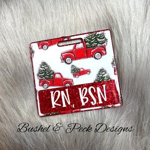 Könnte beinhalten: Roter und weißer Weihnachts-Badge mit einem roten Lastwagen, der einen Weihnachtsbaum transportiert. Der Badge trägt den Text "RN BSN" in rotem Glitzer.
