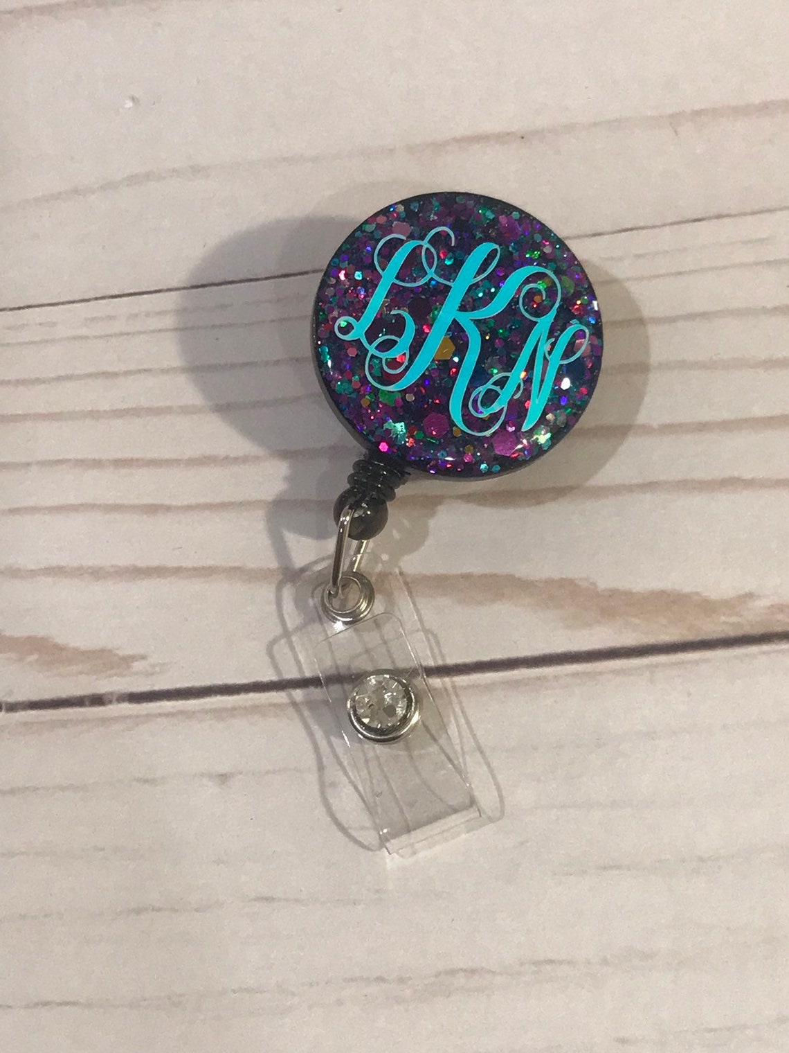 Resin Badge Reel that's sparkly pink with initals LPN.